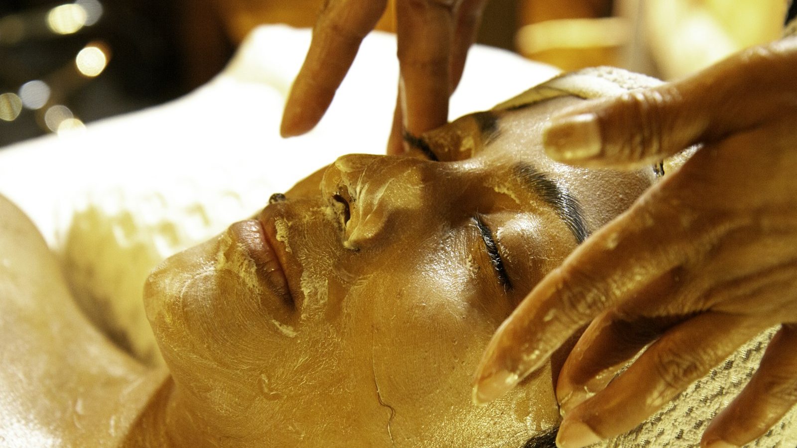 Gold facials: therapist massaging a gold mask into a client's face