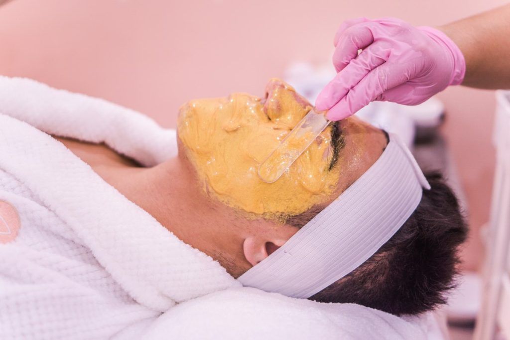 Gold facials: beautician applying a golden face mask