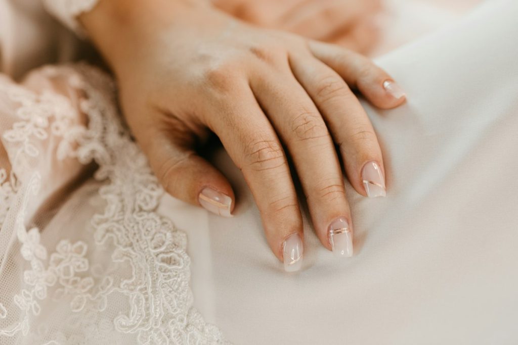 Nail treatments: hands with neat natural nails on white lace
