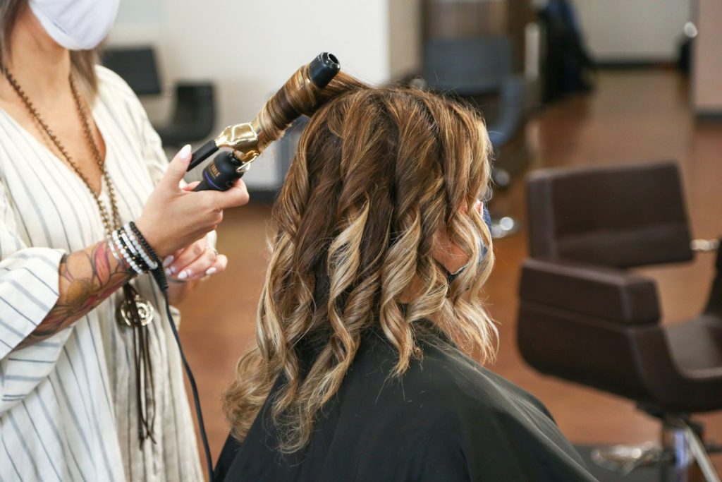 Hair treatments: stylist curling balayage hair in a salon