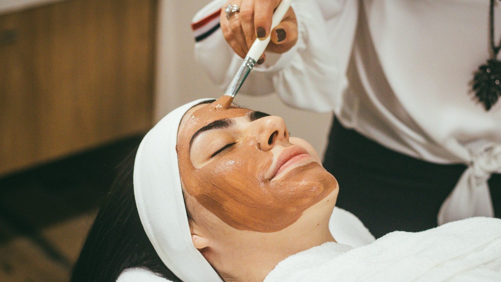 Whitening facial: beautician applying a face mask with a brush