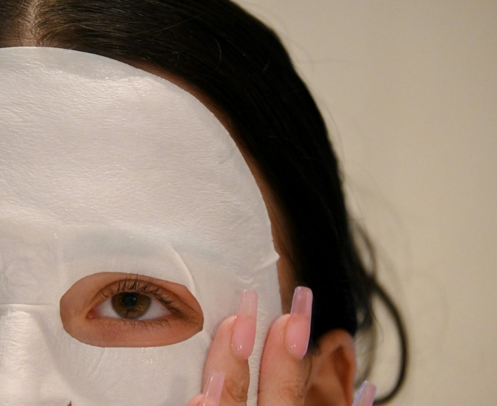 Whitening facial: woman wearing a white sheet face mask