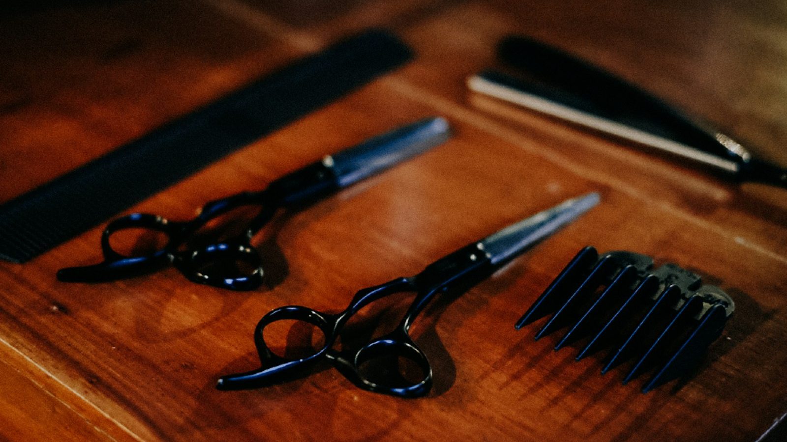 Hair salon in Majan: hairdressing scissors and combs on a wooden table