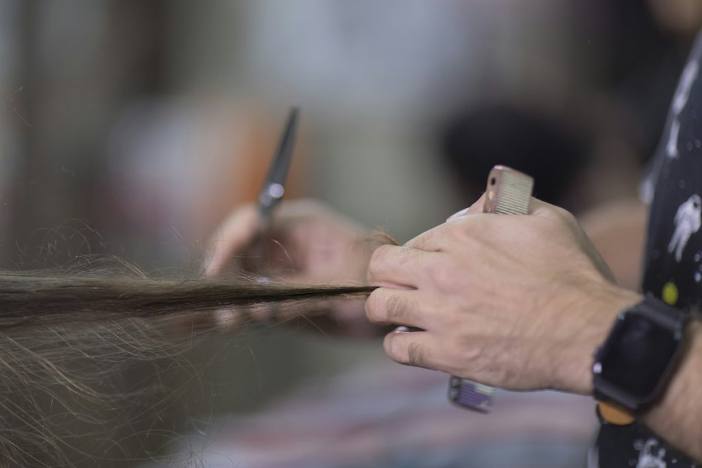 Hair salon in Majan: hairdresser trimming a section of long hair