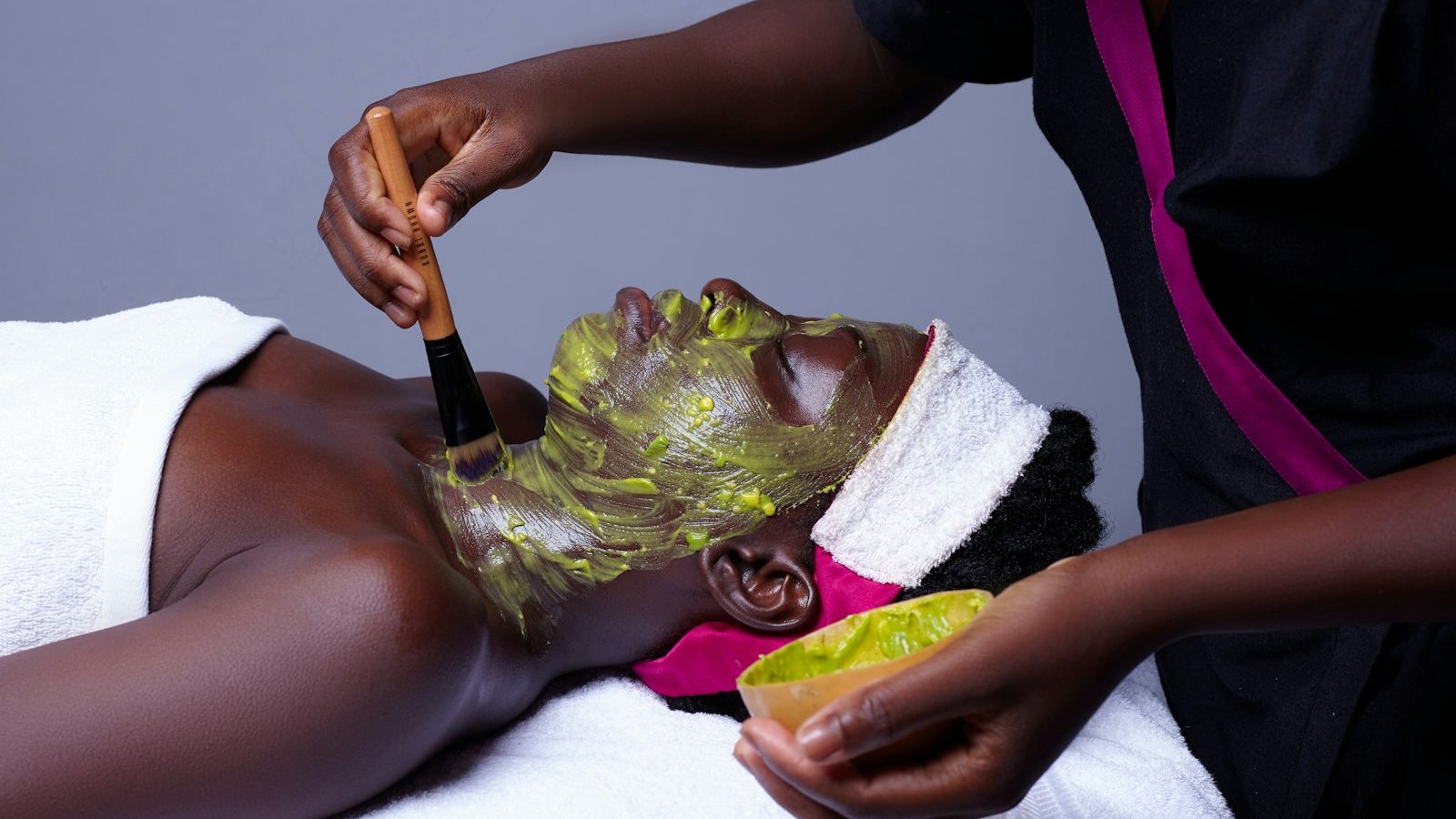 Gold facial good for skin: beautician applying a green face mask