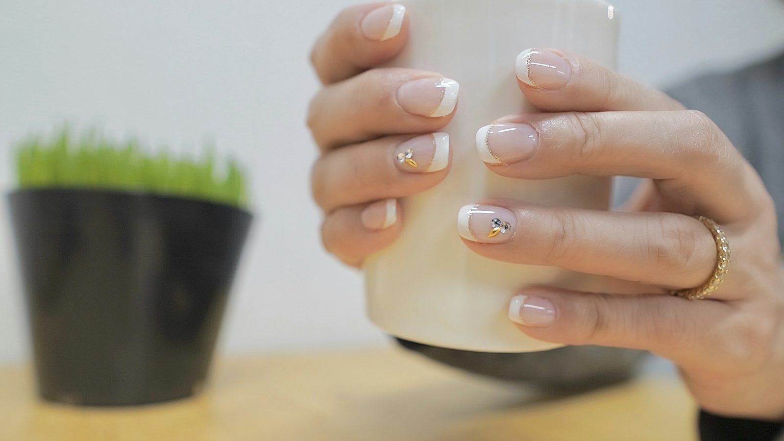 Manicure or pedicure: french manicure nails holding a white cup
