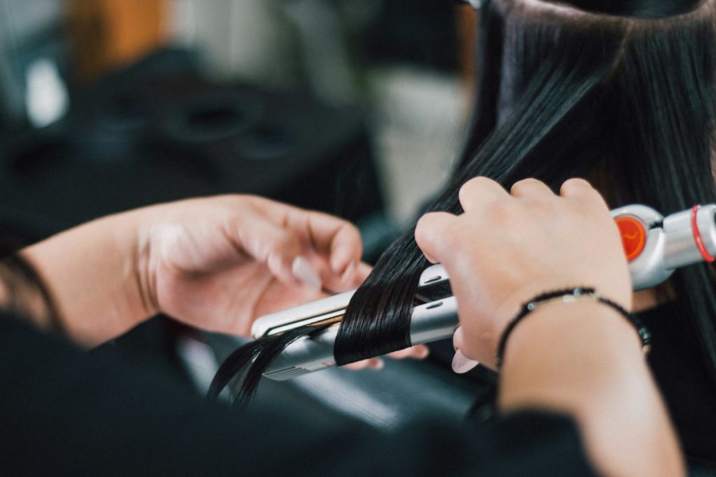 Hair salon near me within 400m open now: flat iron straightening dark hair in a salon
