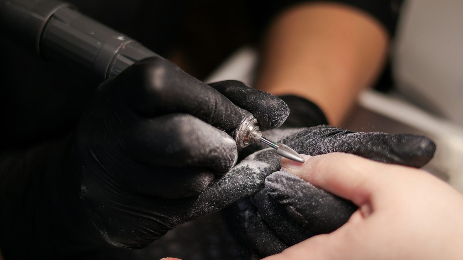 Nail salon near me within 400m: nail technician filing nails with an e-file