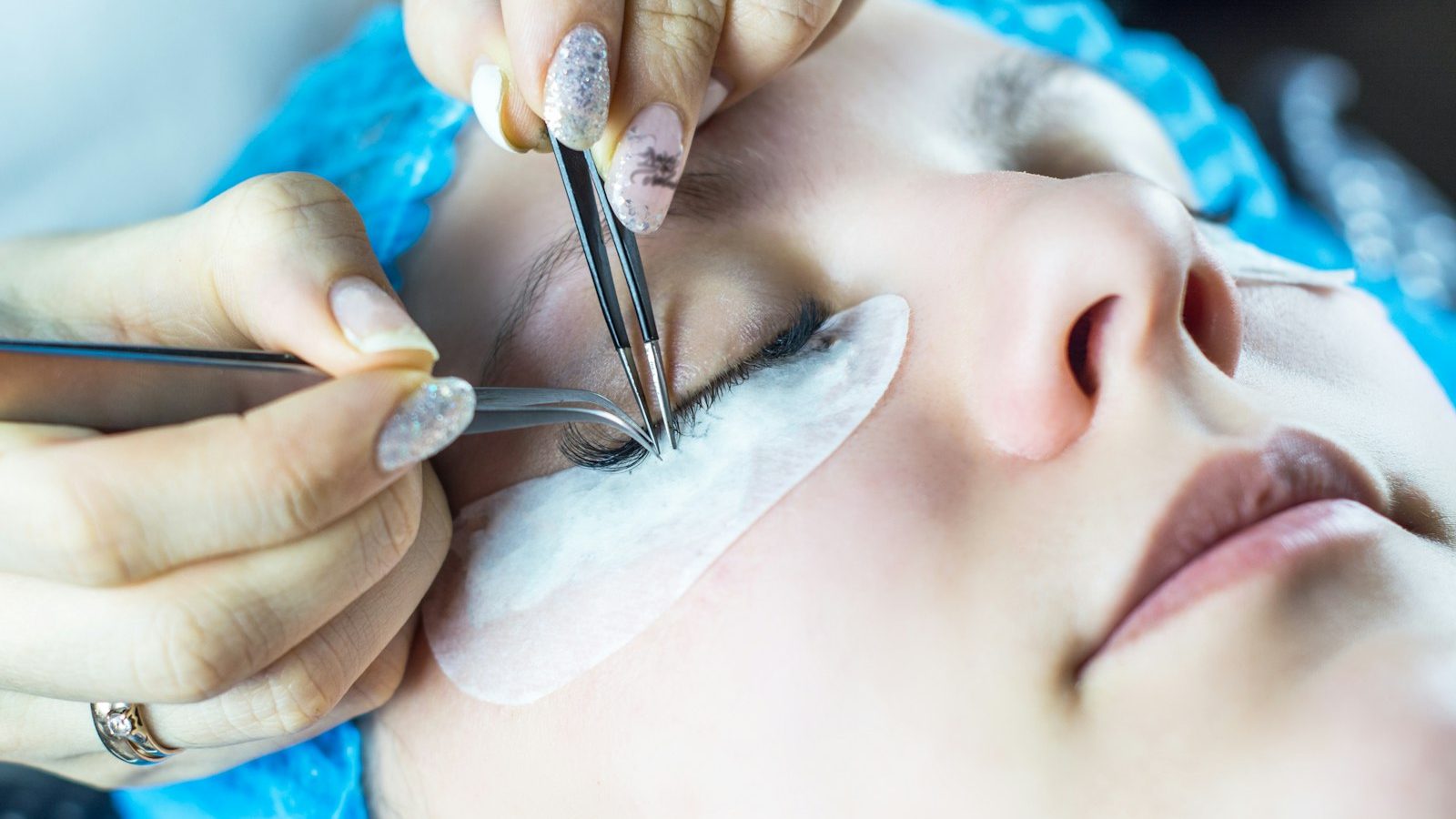 Best parlour near me within 400m: lash technician applying eyelash extensions with tweezers