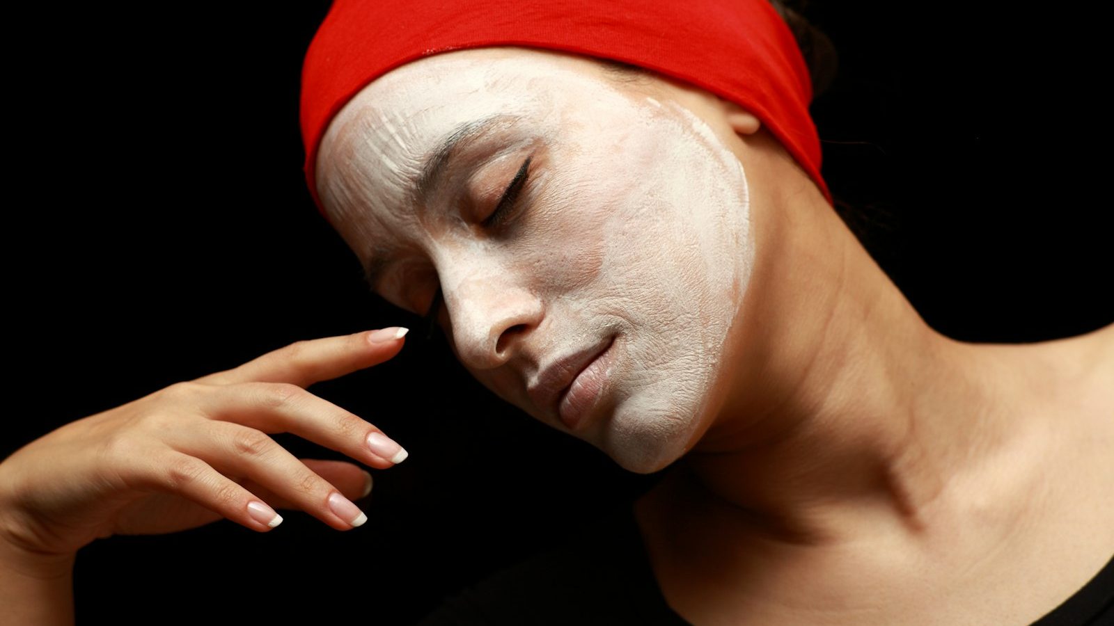 Facial treatment in Majan: woman relaxing with a white clay face mask and red headband