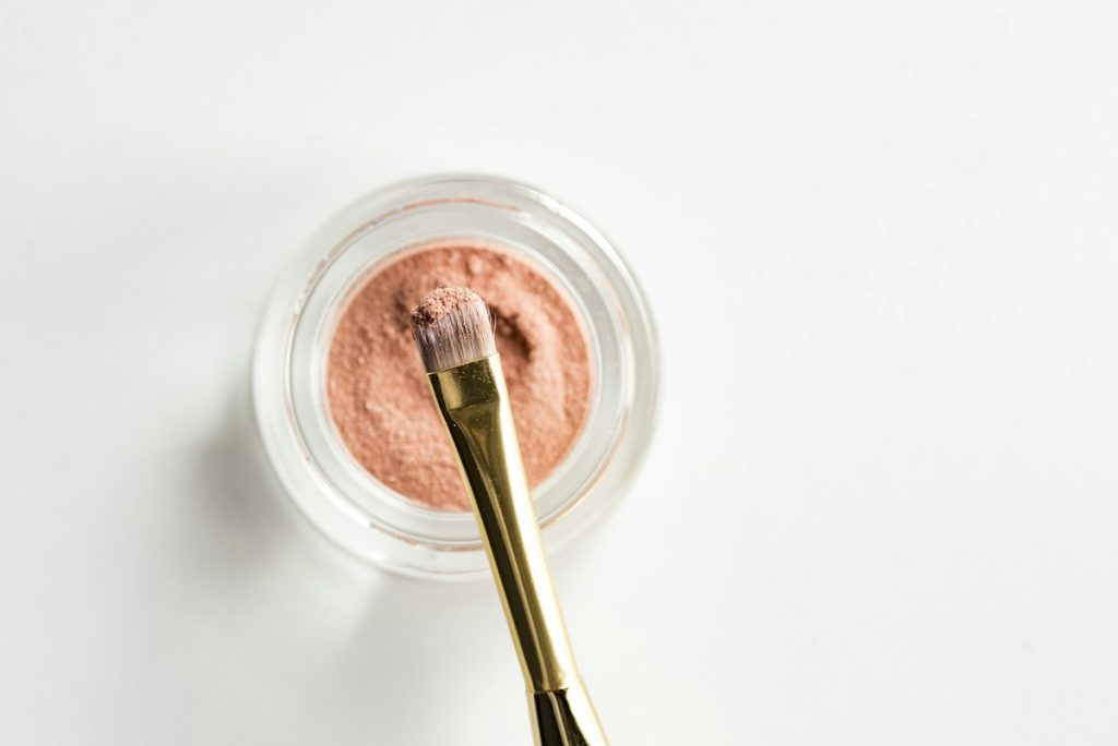 Facial treatment in Majan: pink clay face mask powder in a glass jar with a brush