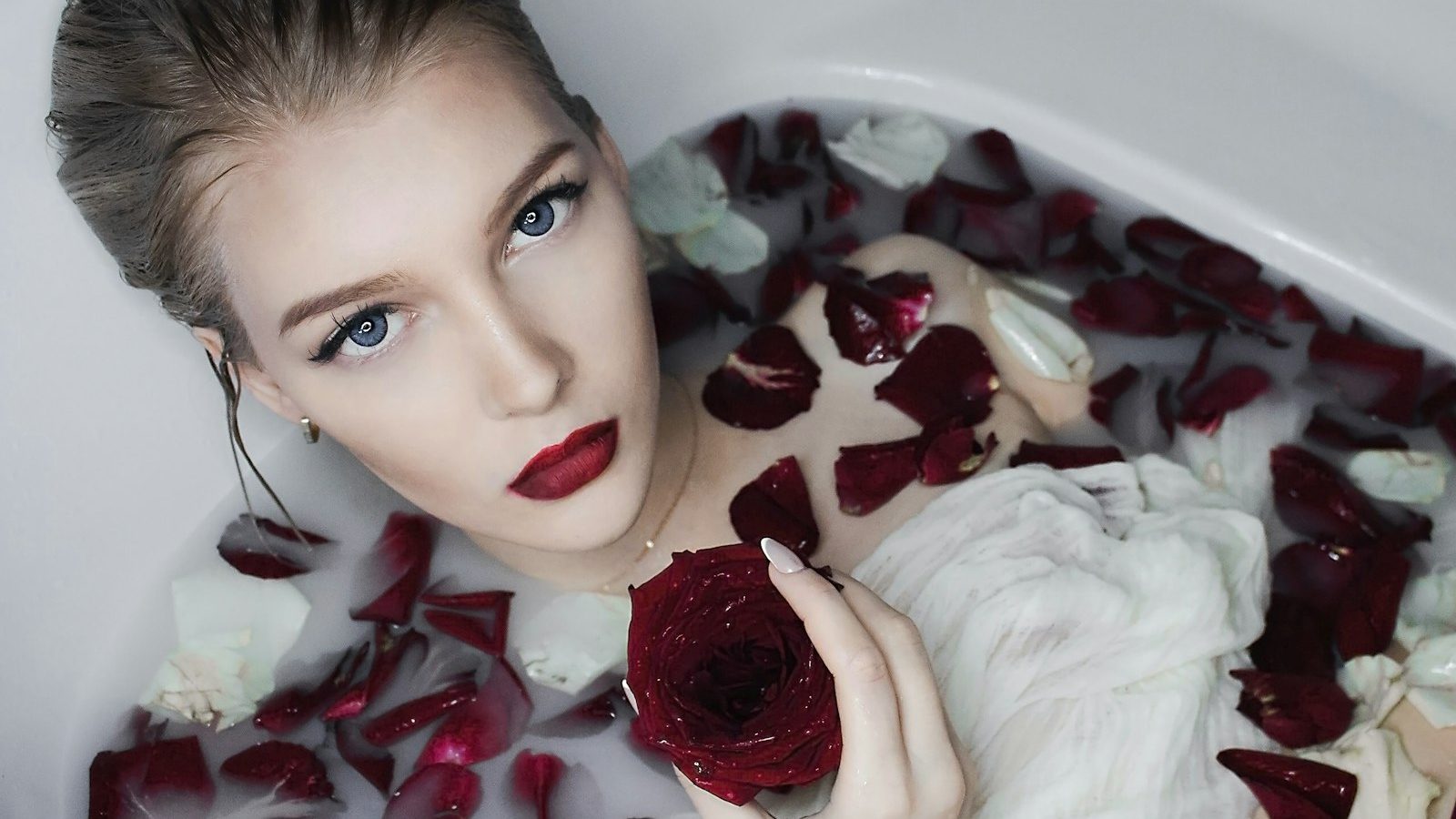 Moroccan baths: woman relaxing in a milk bath with red rose petals