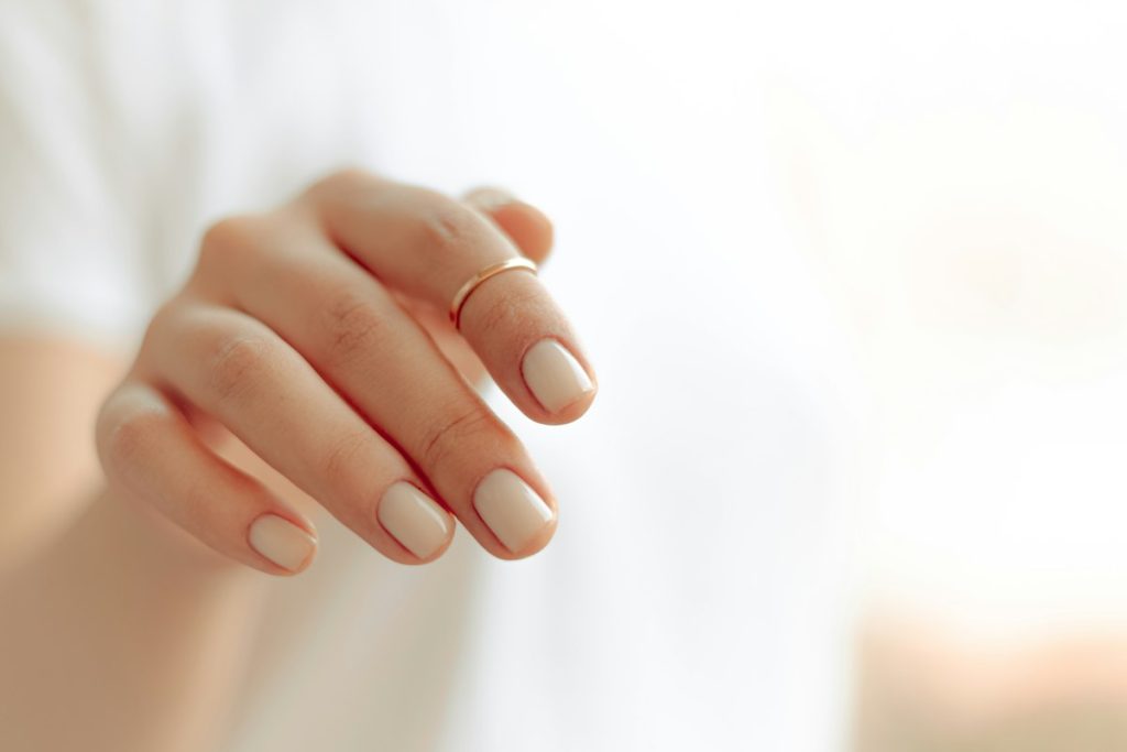 Nail design: nude almond nails and a gold ring