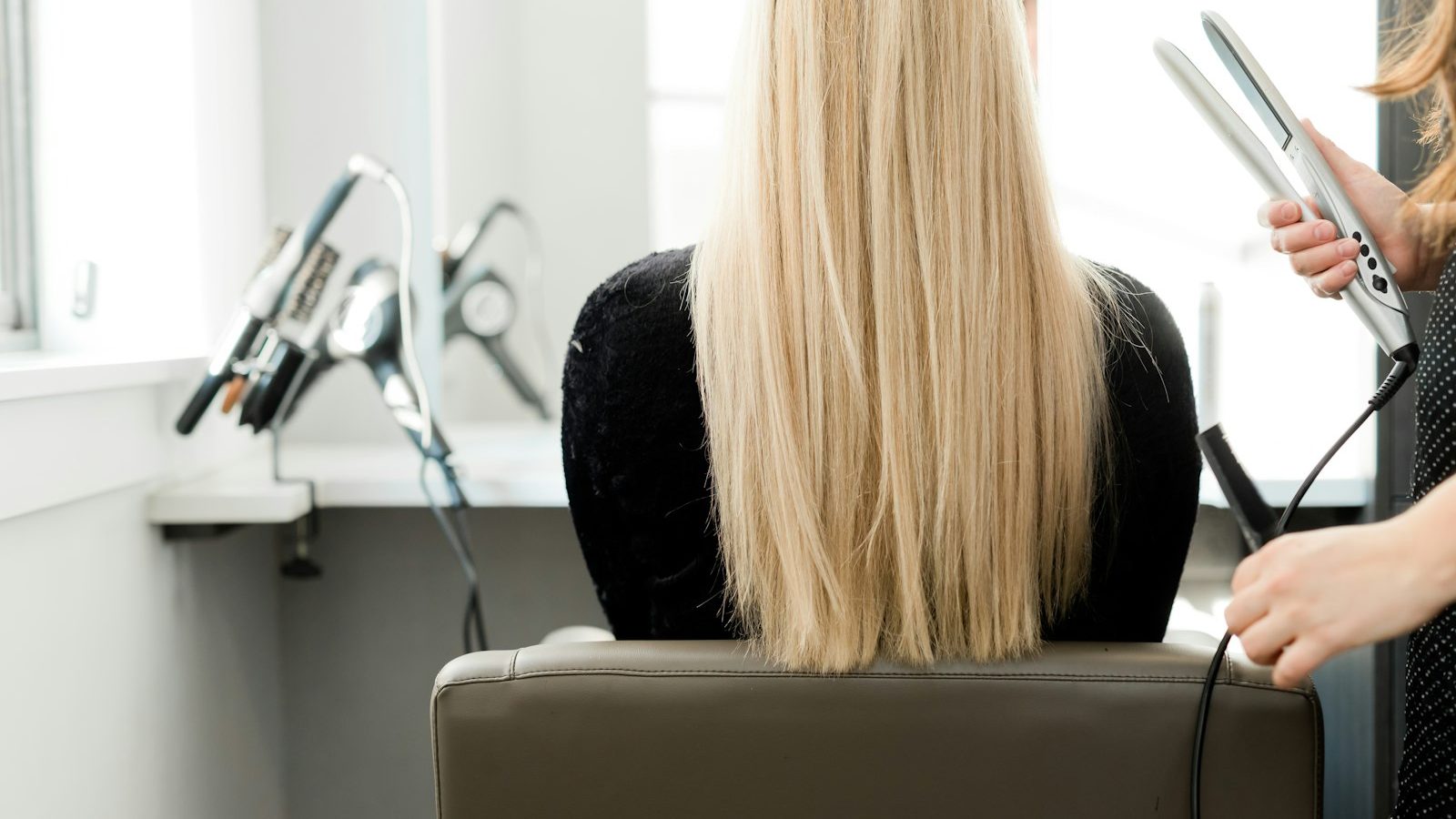 Reduce hair fall: stylist straightening long blonde hair in a salon
